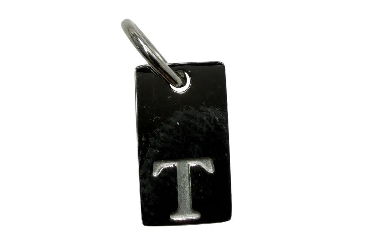 Polished black rectangular tag with raised silver letter T