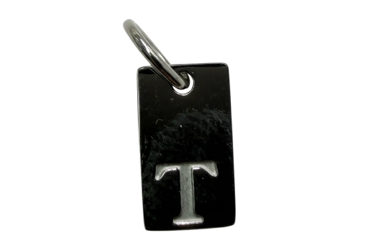Polished black rectangular tag with raised silver letter T