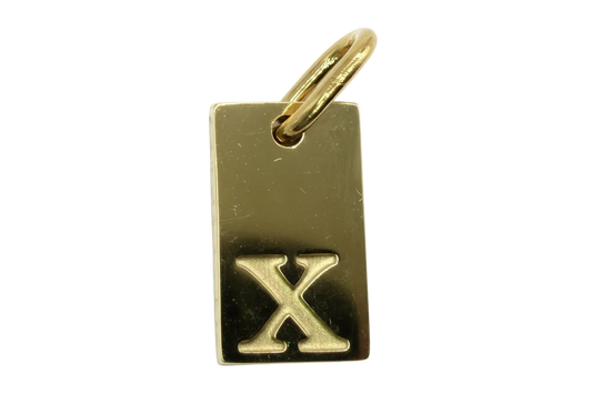 Gold rectangular tag with raised letter X on a polished surface