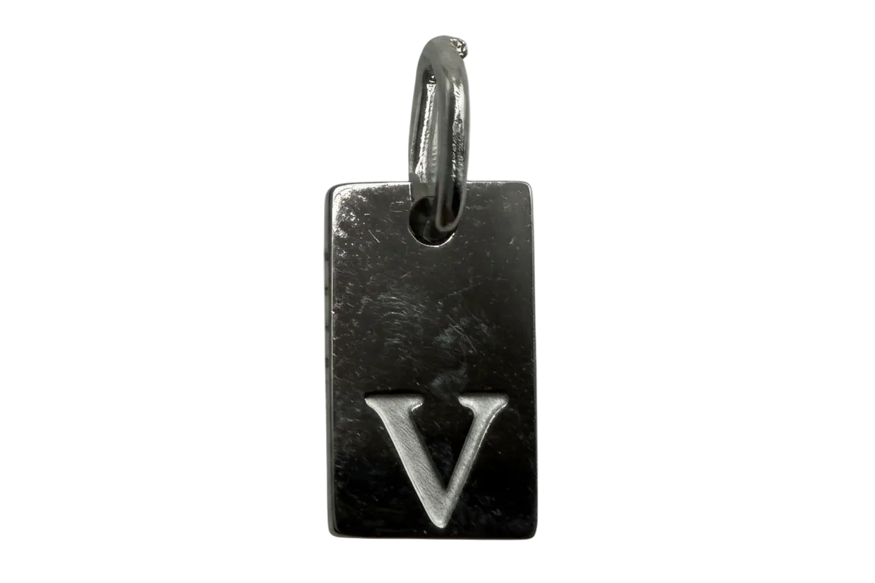 Polished silver rectangular tag with engraved letter V on black background