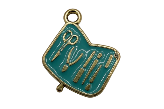 Teal enamel art tools plaque with gold outline and raised scissors, brush, and pencil details
