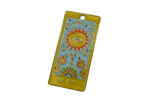 Gold-edged enamel tarot card with sun and eye motif on sky-blue background, with flowers and rainbow