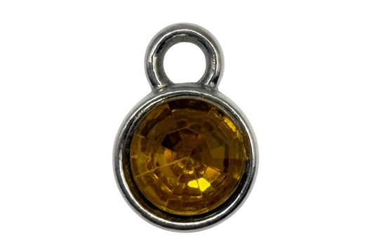 Round faceted amber-yellow gem in a polished silver frame