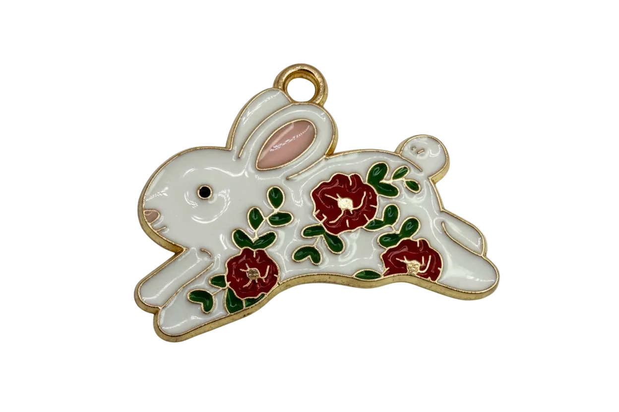 White rabbit charm with red flowers and green leaves, gold outline and pink ear detail