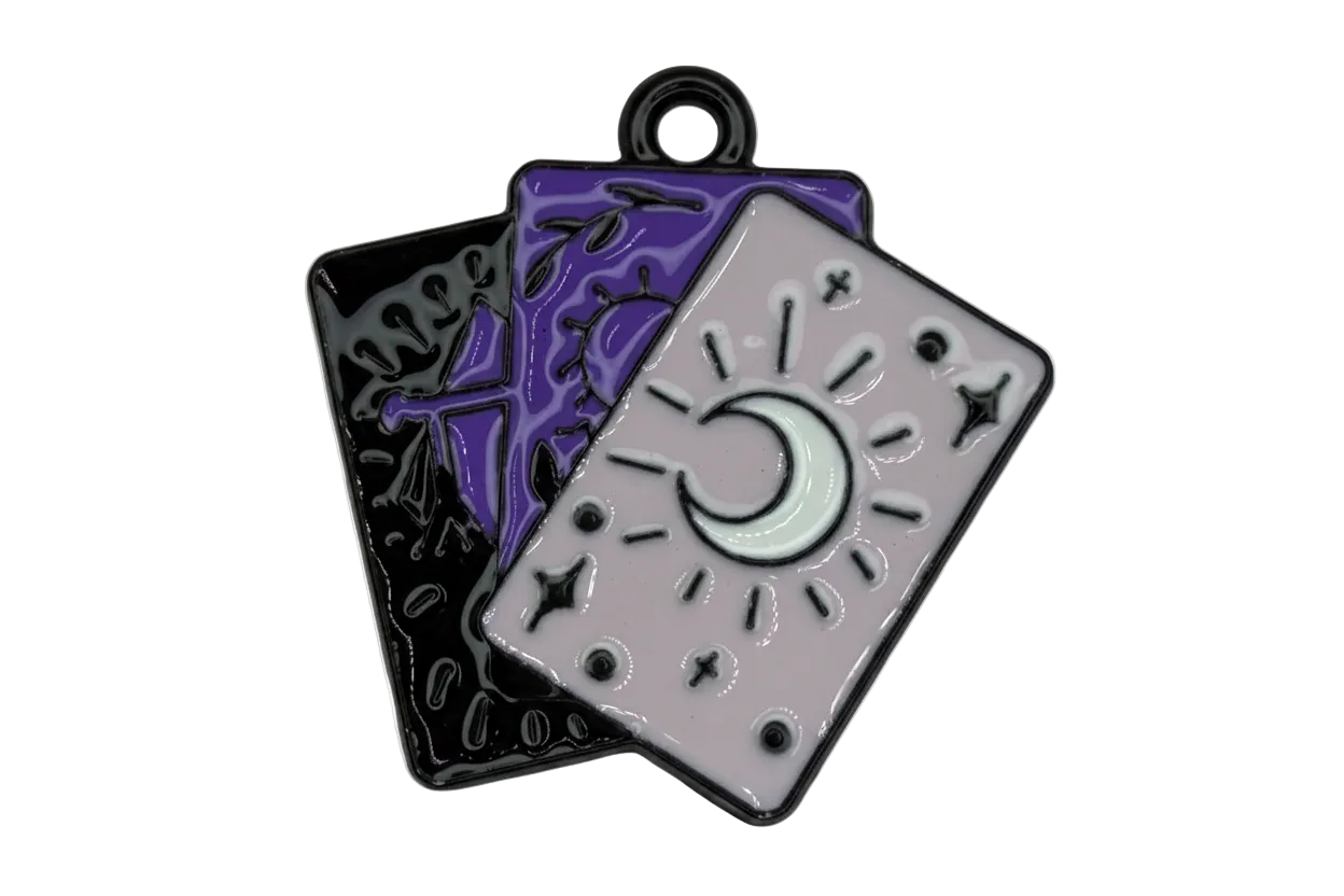 Glossy enamel tarot card trio with crescent moon on lavender card, layered over purple and black cards