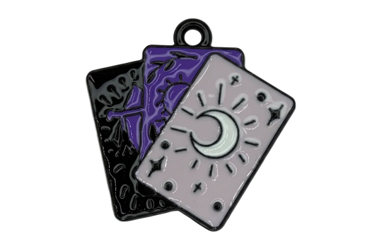 Glossy enamel tarot card trio with crescent moon on lavender card, layered over purple and black cards