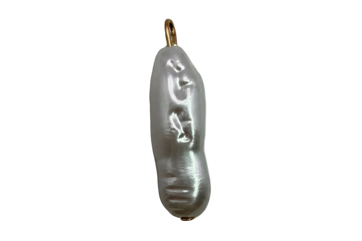Elongated baroque pearl with carved face detail and gold accents on black background