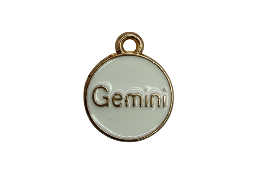 White round enamel medallion with raised gold "Gemini" lettering and gold rim