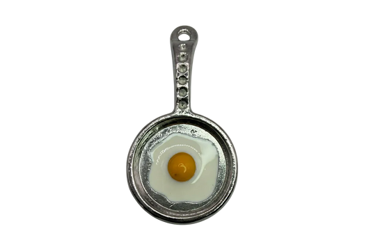 Silver skillet charm with a glossy sunny-side up egg, white enamel and yellow yolk