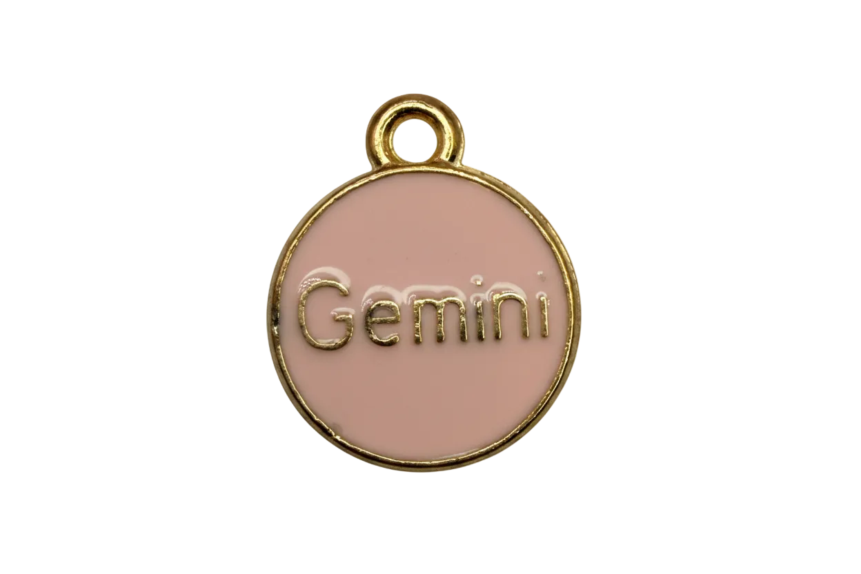 Blush pink enamel coin with raised gold Gemini lettering and a gold rim