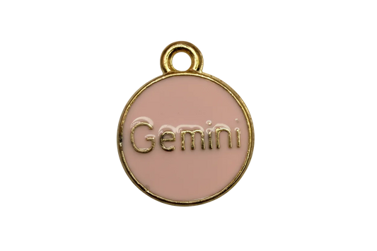 Blush pink enamel coin with raised gold Gemini lettering and a gold rim
