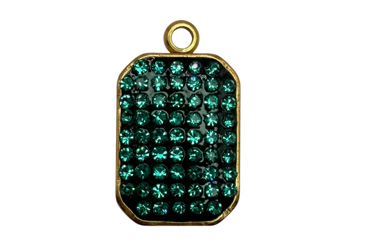 Gold-framed rounded rectangle plate with pavé emerald green crystals over a glossy black base