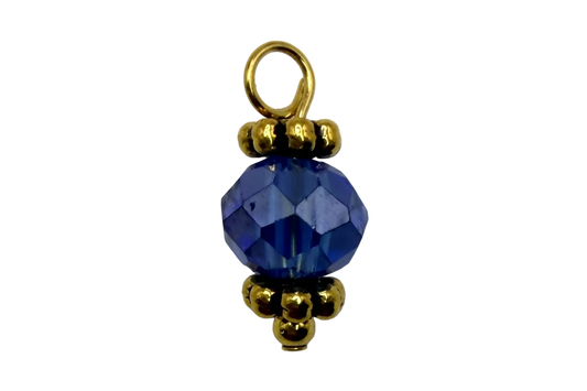 Faceted sapphire blue orb gem with gold bead accents on black background