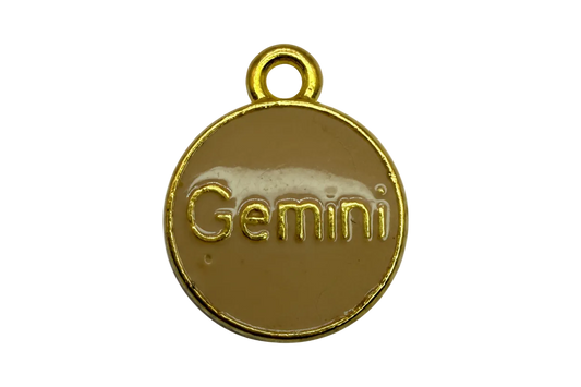 Round tan enamel disc with raised gold Gemini lettering and gold border