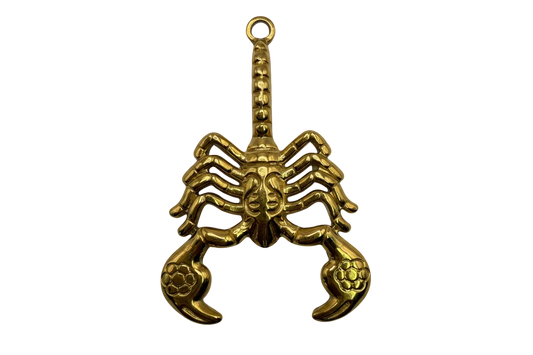 Gold sculpted scorpion charm with arched tail and detailed pincers on black background