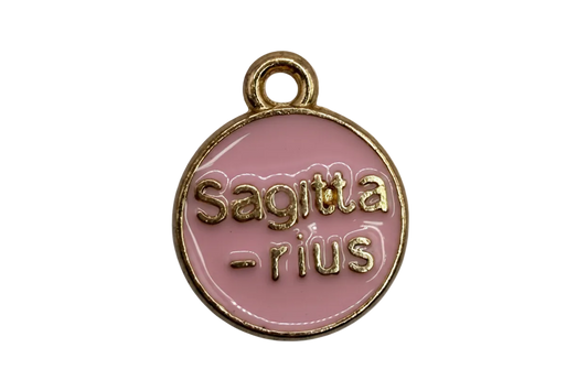 Round pink enamel zodiac coin with raised gold “Sagittarius” and “sun” lettering