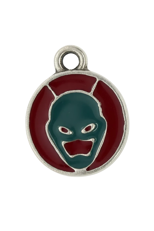 Round silver-tone medallion with red enamel background and teal demon face motif