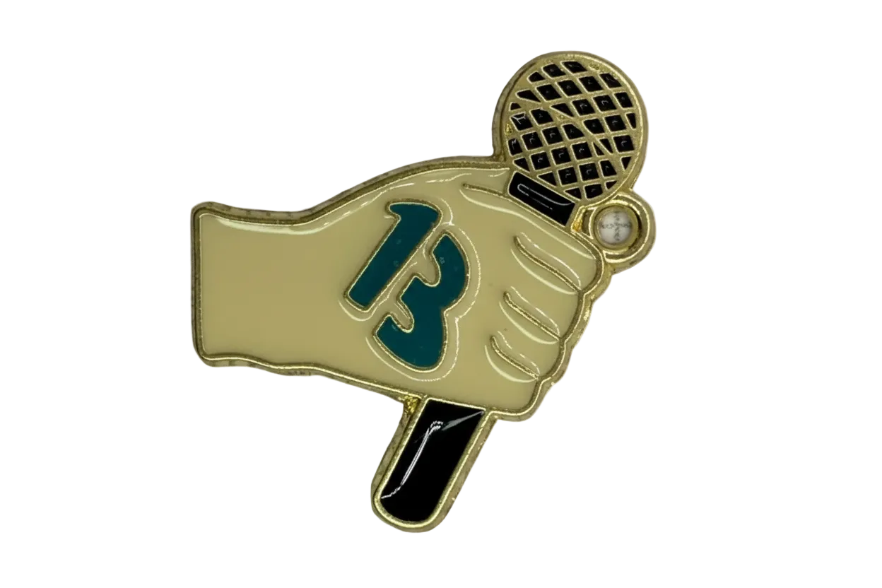 Gold-outlined enamel gloved hand holding a black tennis racket with teal detail and a small white gem