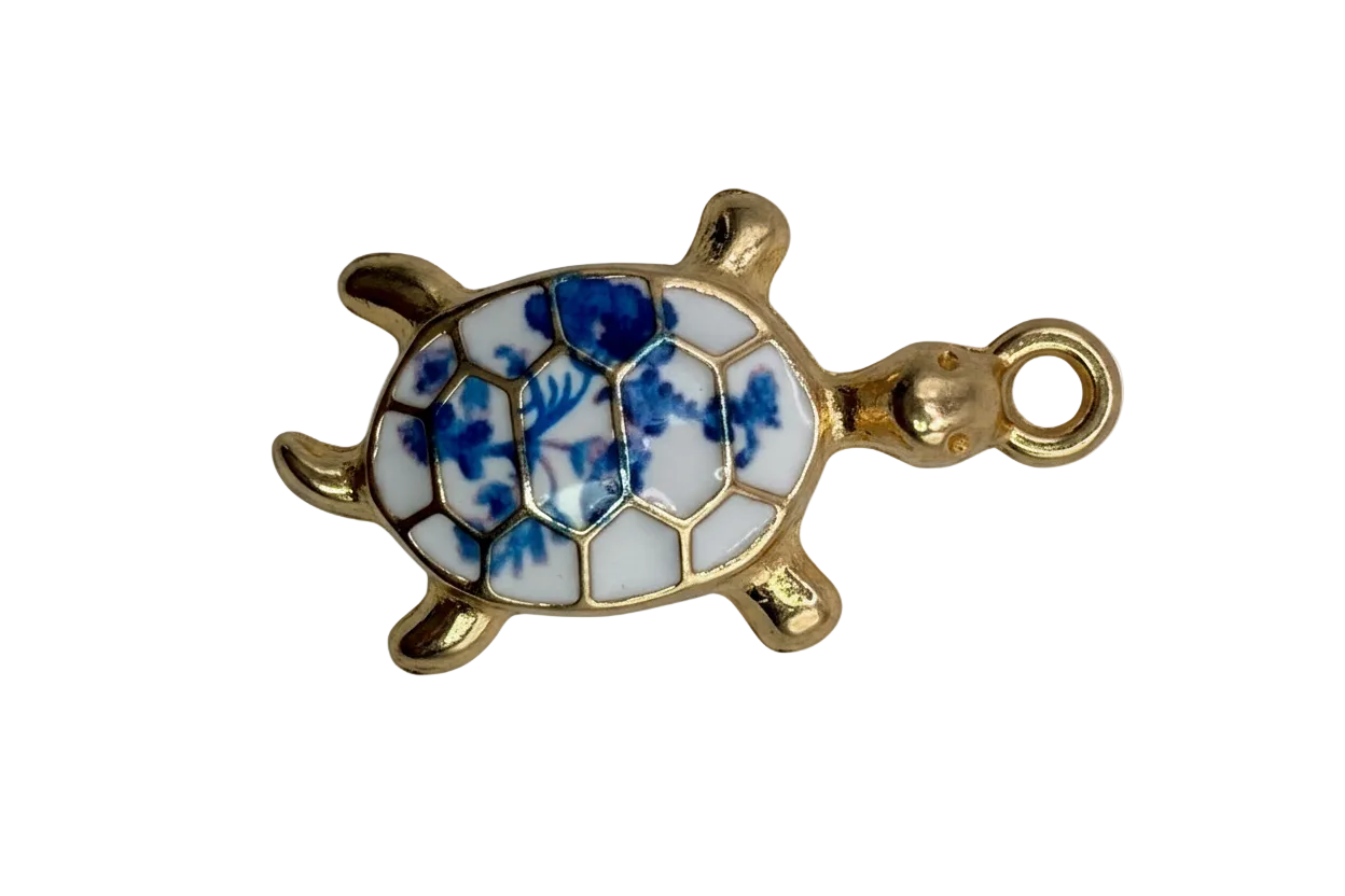 Gold sea turtle charm with glossy white shell and blue floral pattern