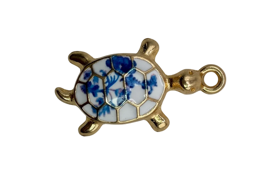 Gold sea turtle charm with glossy white shell and blue floral pattern