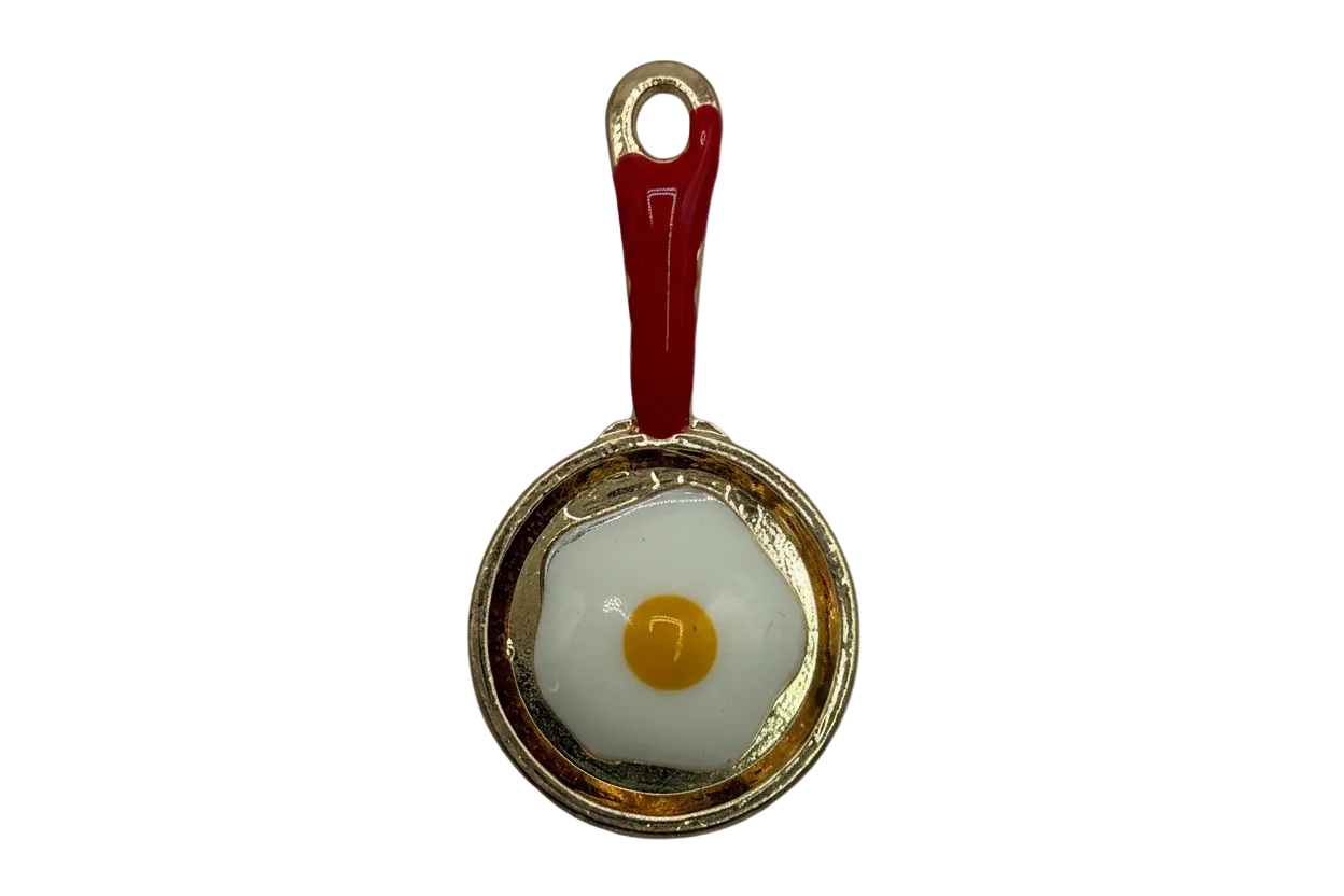 Gold skillet with red handle and sunny-side-up egg in white enamel with yellow yolk