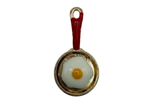 Gold skillet with red handle and sunny-side-up egg in white enamel with yellow yolk