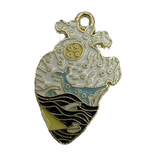 Gold-tone anatomical heart with white enamel, blue whale, black waves, and small sailboat detail