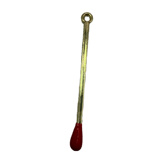 Polished gold matchstick charm with glossy red tip on black background