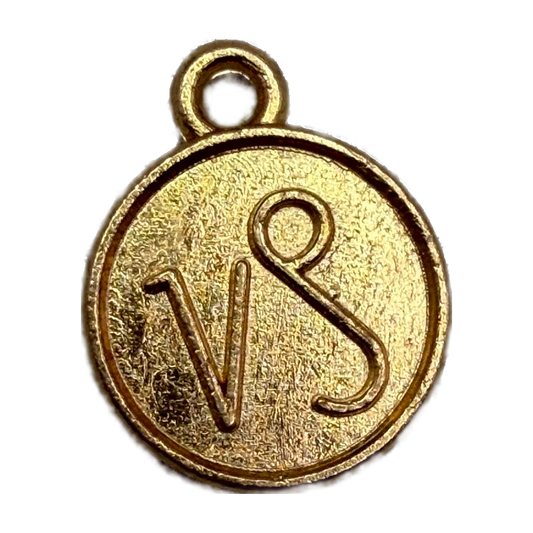 Round gold medallion with raised VS monogram and textured finish