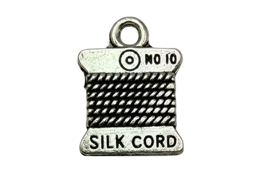 Antiqued silver spool charm with black cord texture and engraved “SILK CORD” and “NO 10” text