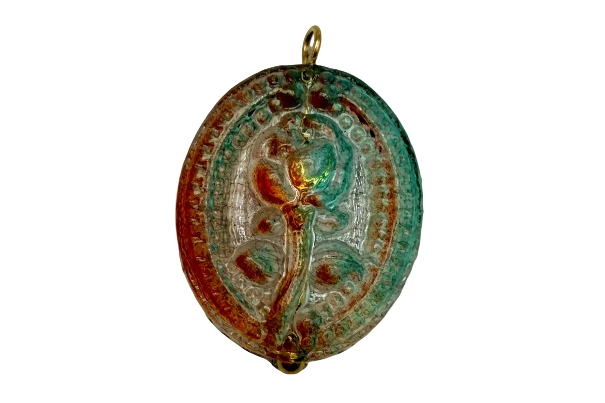 Antiqued oval floral medallion charm in gold with teal verdigris patina and warm amber tones