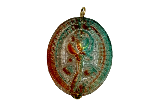 Antiqued oval floral medallion charm in gold with teal verdigris patina and warm amber tones