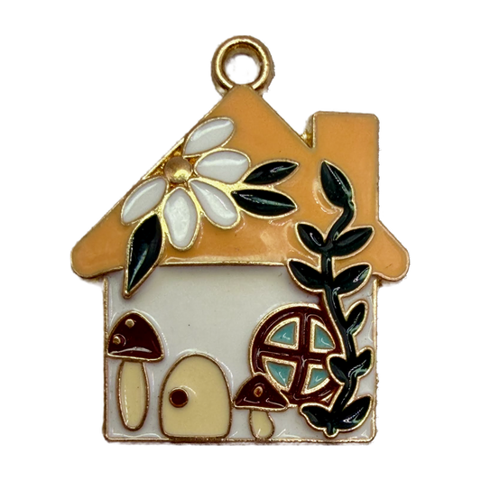 Gold-outlined enamel cottage house with tan roof, white flower, dark vine, mushrooms, and teal window