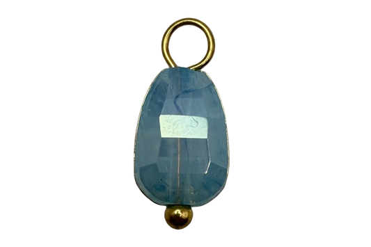 Faceted sky blue oval crystal gem with gold accents on black background