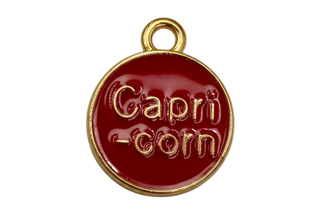 Round red enamel Capricorn coin with raised gold lettering and gold edge