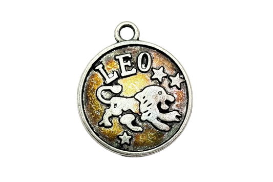 Antiqued silver round Leo zodiac medallion with raised lion and stars on amber enamel