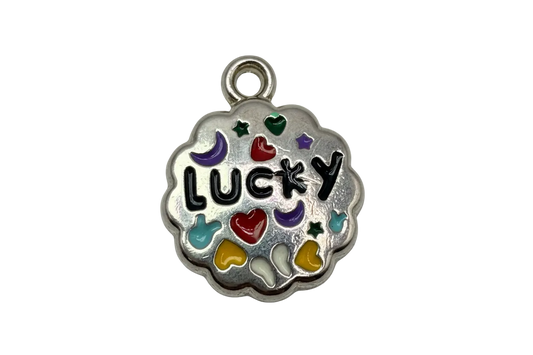 Silver-tone scalloped coin charm with black "LUCKY" lettering and colorful enamel hearts, stars, and moons