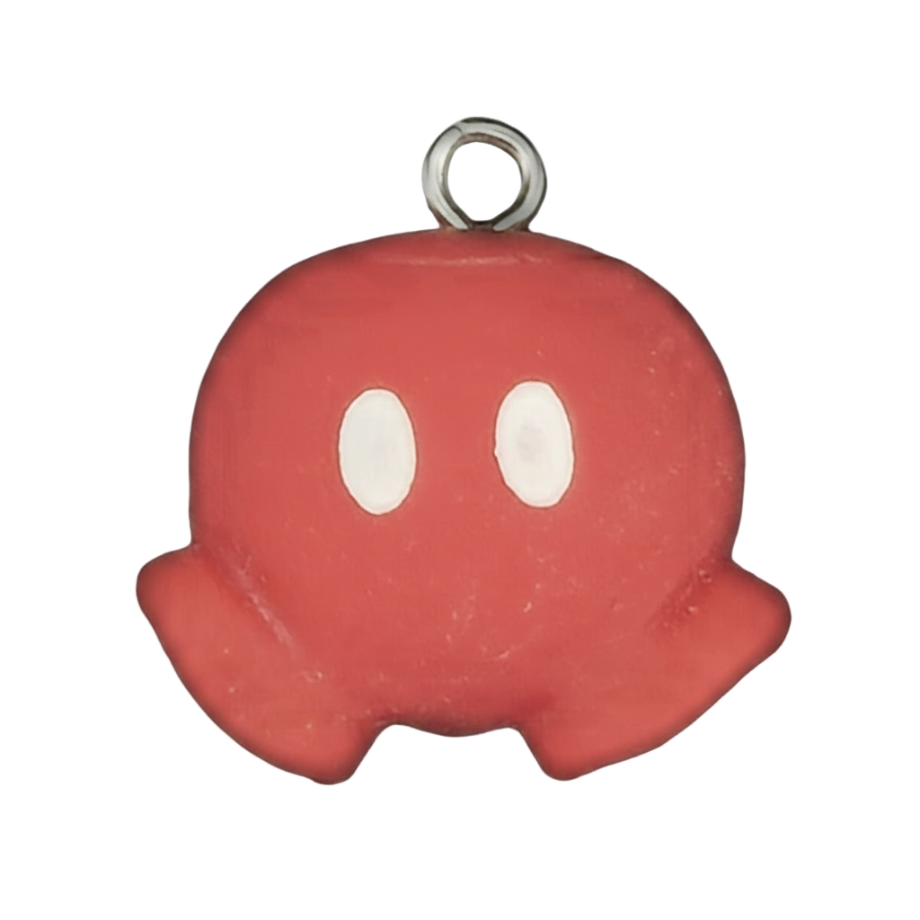 Close-up of a red ghost charm with white oval eyes on a black background.