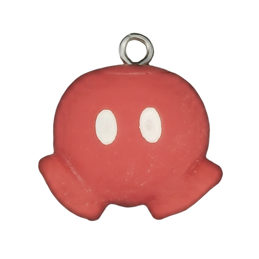 Close-up of a red ghost charm with white oval eyes on a black background.