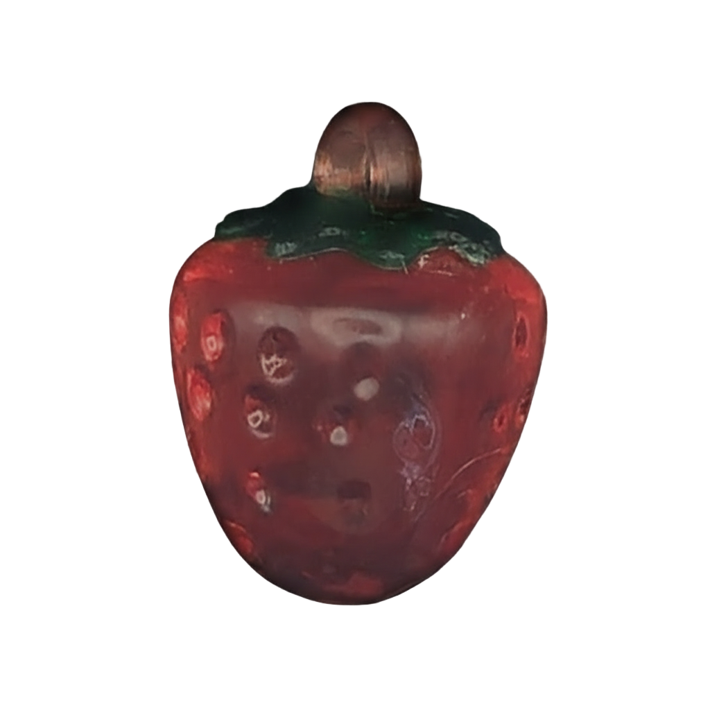 close-up red strawberry-shaped charm with green top on black background