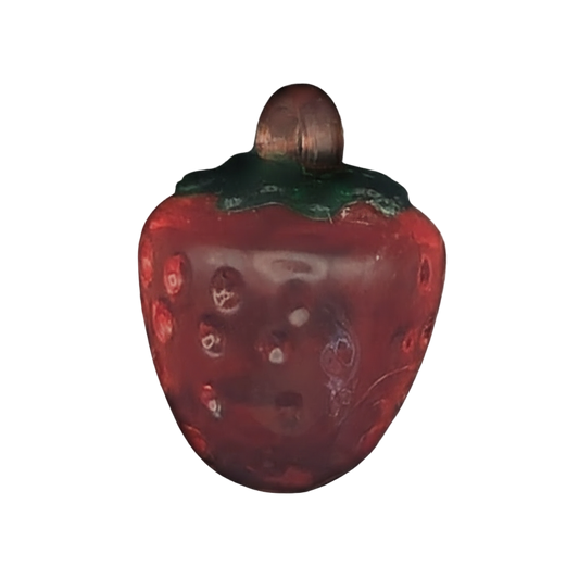 close-up red strawberry-shaped charm with green top on black background