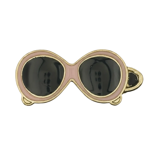 close-up of pink and black sunglasses charm with gold edging on black background