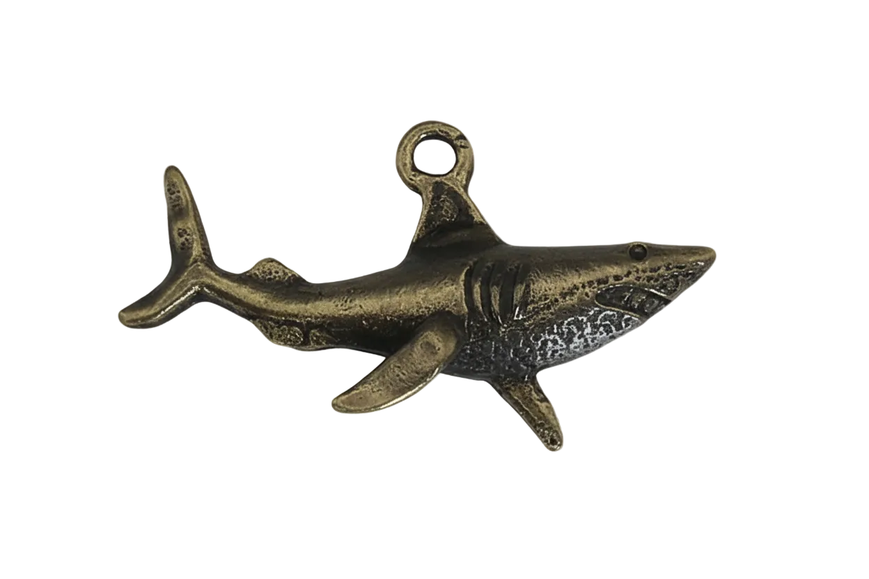 close-up of bronze-tone metal shark charm on black background