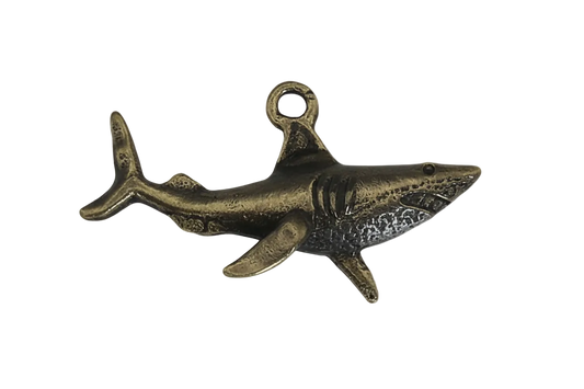 close-up of bronze-tone metal shark charm on black background