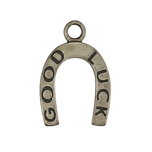 close-up of a gold-tone horseshoe charm reading GOOD LUCK on a black background