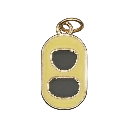 Close-up of yellow enamel soda can pull tab charm with gold-tone edges on a black background.