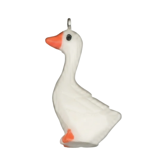 close-up of a white goose charm with an orange beak on a black background