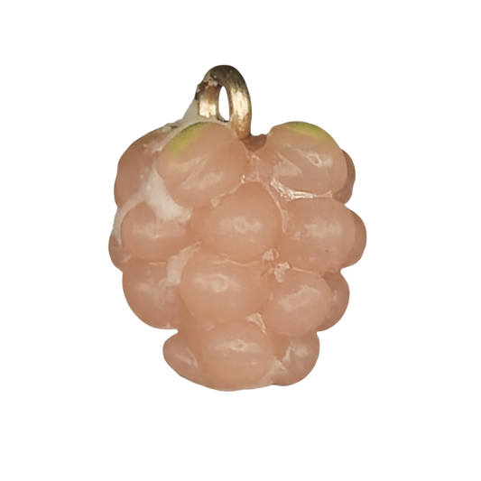 close-up of a small pink raspberry-shaped charm with a gold-tone top on a black background