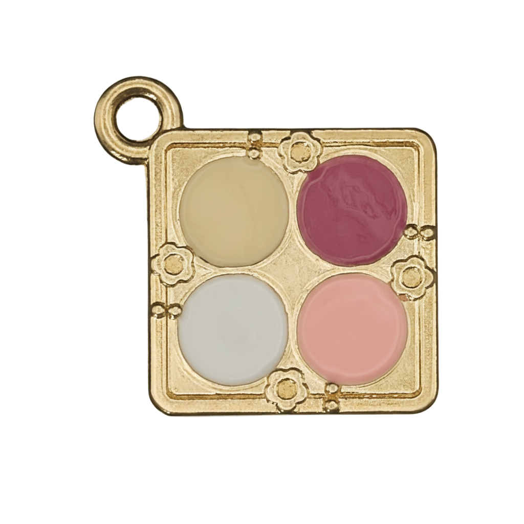 close-up of gold-tone square charm shaped like a four-color makeup palette with yellow, dark pink, white, and peach enamel on black background