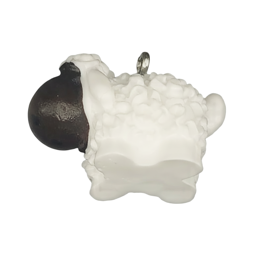 close-up of small white sheep charm with black head on a black background
